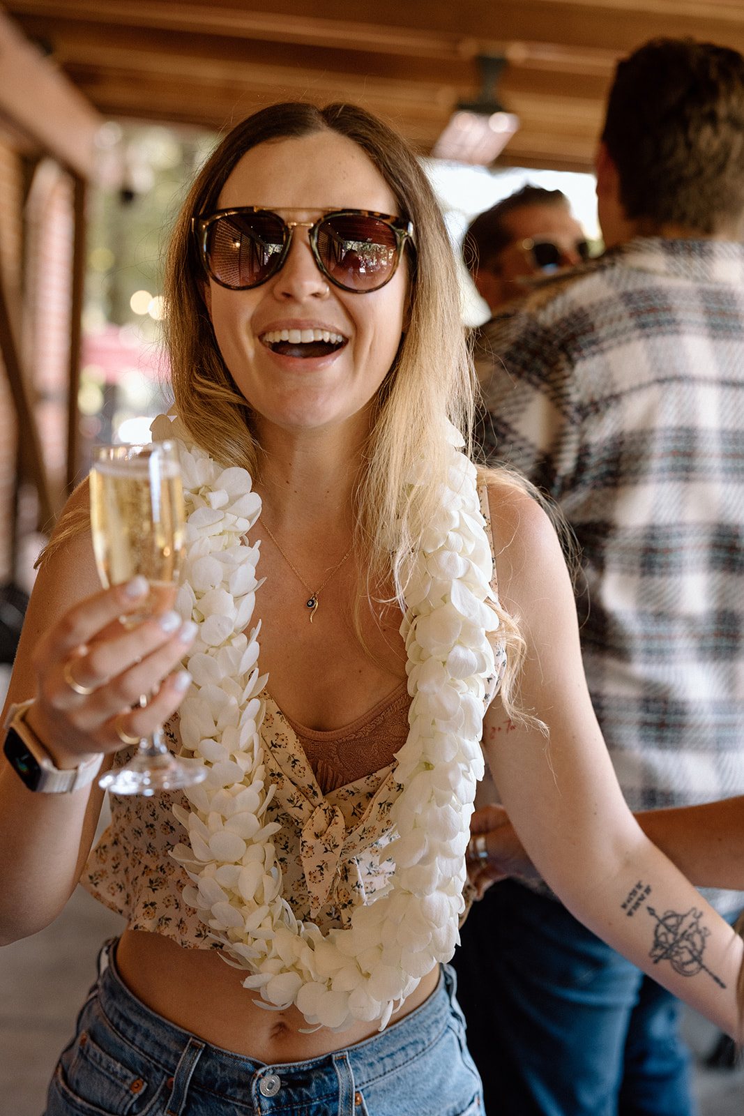Aidan in a white lei laughing with a glass of champagne at Korbel